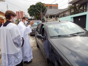 Padre Tiago Síbula abençoando um carro e seus passageiros