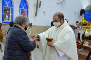 Padre Flávio José entregando a comunhão para uma senhora durante a missa das 15h da festa de Santa Rita de Cássia 2021